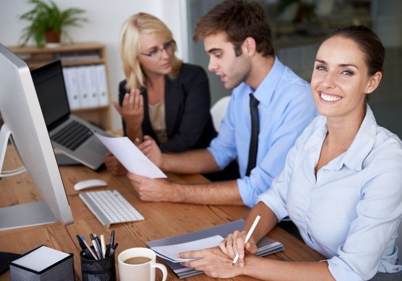 Tres personas en la mesa de trabajo de la oficina.